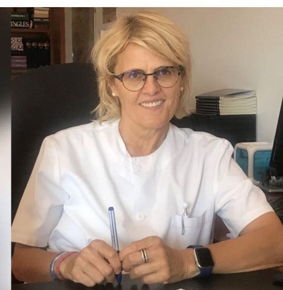 Una mujer con gafas está sentada en un escritorio con un bolígrafo en la mano.
